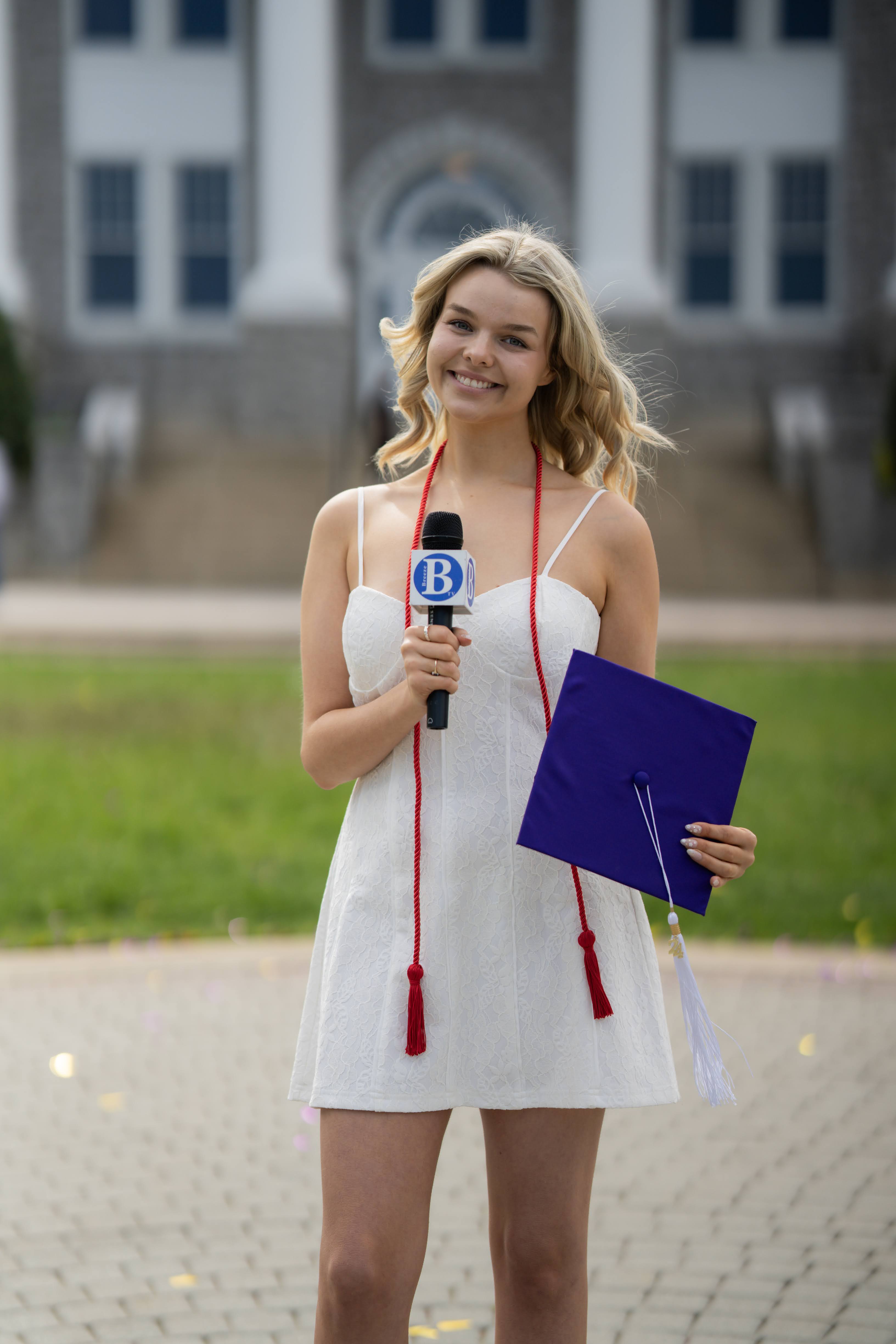 Maggie holding a Breeze TV Microphone and a graduation cap.